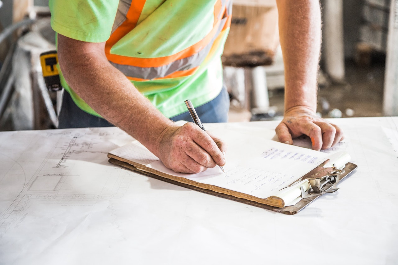 Construction worker reviewing plans and project checklist.